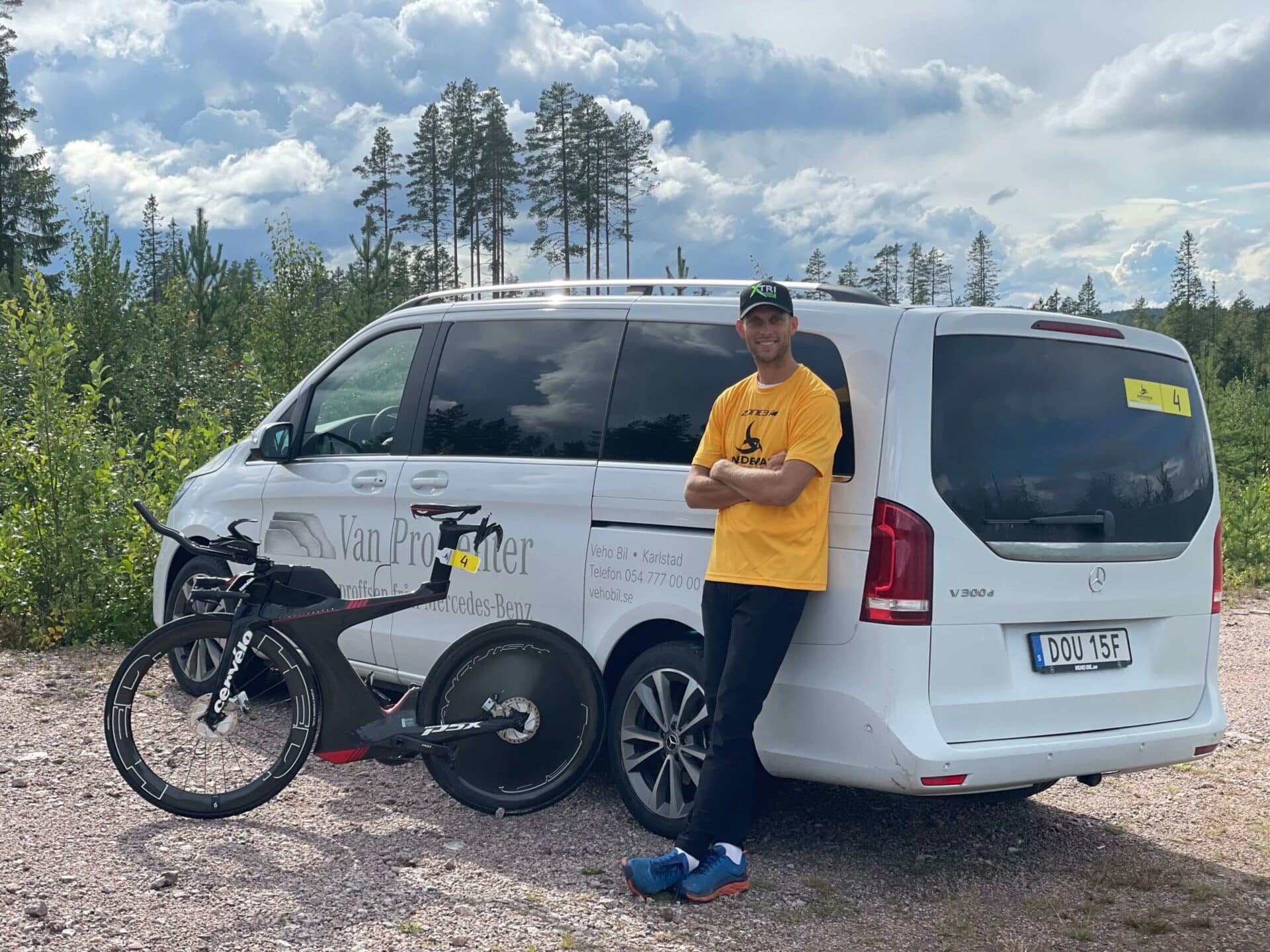 Minivan, en cykel och en person som lutar sig mot bilen